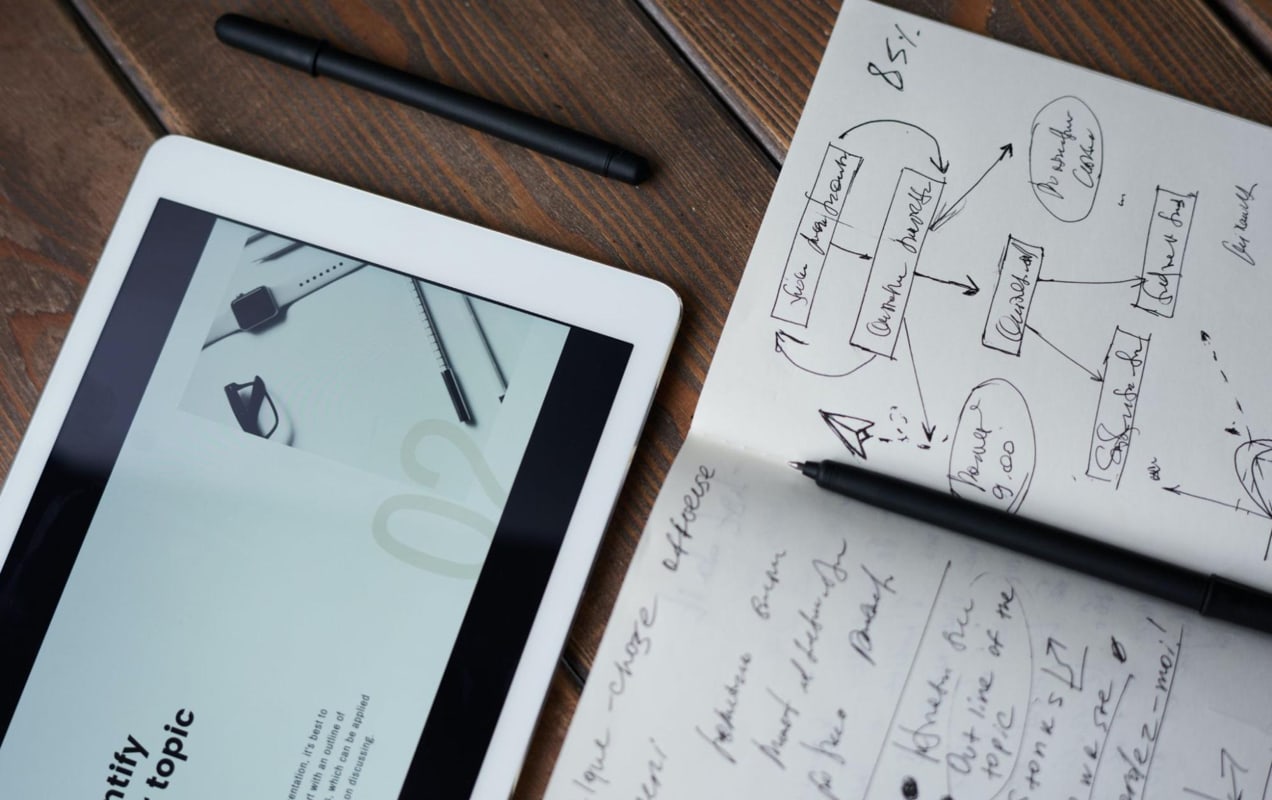 diagram and notes in a notebook, next to a tablet